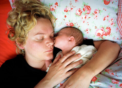 Mother and baby sleeping together peacefully in bed indoors