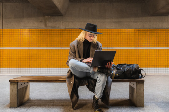 Commuter working on laptop while waiting at urban subway station