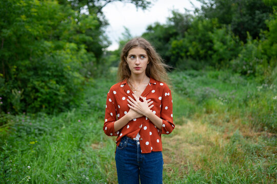 Woman with curly hair in red polka-dot blouse smiling outdoors in summer