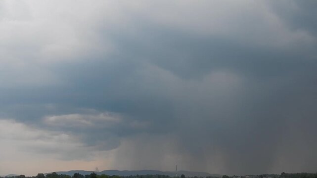 Dark rainy and stormy clouds with lightnings and Praecipitatio rain streaks over horizon of Silesian Beskid mountains in Poland during summer storm. Topics: weather, meteorology, cloud types
