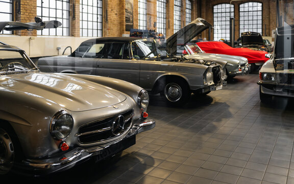Vintage Mercedes-Benz cars in auto repair workshop. Front view of old Mercedes-Benz models, including 300SL and W111 Cabriolet undergoing repairs and maintenance. Berlin, Germany - January 14 2026