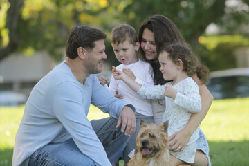 Fototapeta premium Happy family with young children spending time together in a park, smiling and interacting in a natural outdoor lifestyle scene.