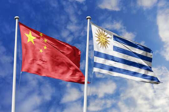 China and Uruguay flags waving in a clear blue sky, symbolizing a powerful diplomacy, a strategic partnership, and a shared vision of unity for a sustainable future.