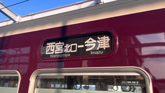 Hankyu Railway train side destination indicator showing the Imazu Line route between Nishinomiya-Kitaguchi and Imazu stations on a maroon carriage - Hyogo, Japan, August 30, 2025