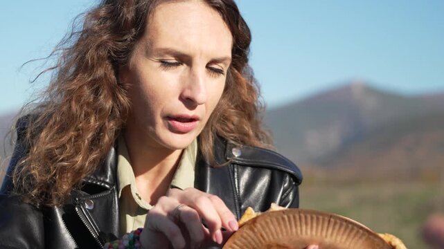 Woman eating picnic fried bread outside during sunny mountain vacation trip