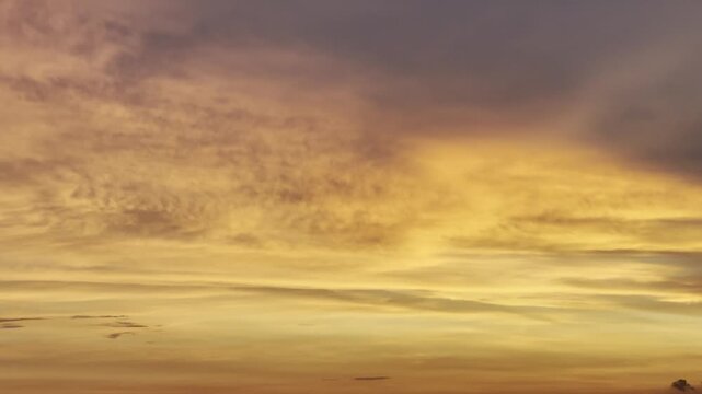 Beautiful sunset sky background with layers of altocumulus and cirrus clouds illuminated by golden evening light.