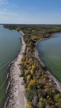 Vertical aerial drone shot of the peninsula on Hecla Island Manitoba. Drone moving backward revealing shoreline, Lake Winnipeg, forest, and trees along the island.