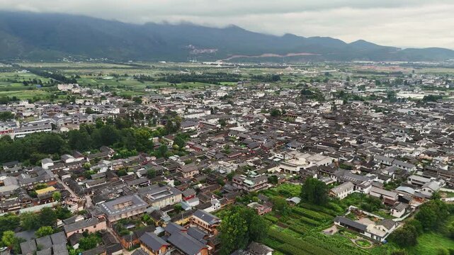 Baisha town traditional houses and farmland with mountains and clouds near Fuguo Monastery Yunnan, panoramic aerial dolly