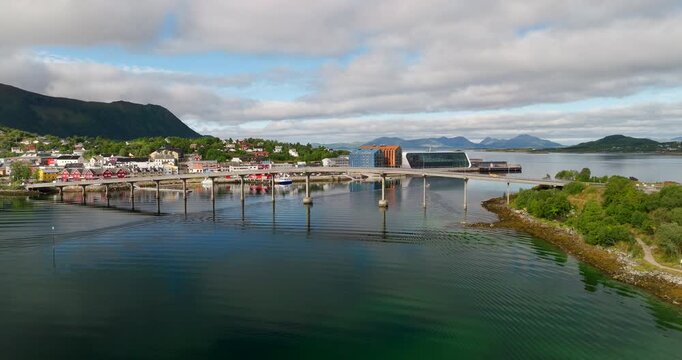 Cinematic aerial reveal of B&oslash;r&oslash;y Bridge and the waterfront at Stokmarknes, Norway, with calm fjord water, modern architecture and scenic coastal surroundings