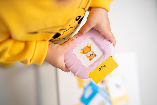 Toddler playing with a pink electronic flashcard learning toy