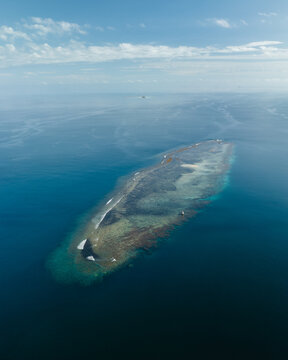 Aerial view of turquoise waters embrace a coral reef island, a haven of biodiversity amidst the vast ocean's expanse, Goro, South Province, New Caledonia.