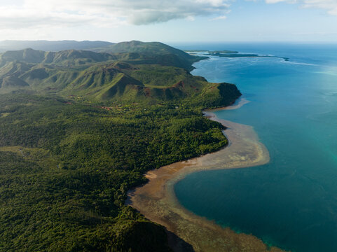 Aerial view of the rugged coastline where emerald forests meet the turquoise sea, creating a vibrant contrast of natural beauty, Goro, South Province, New Caledonia.