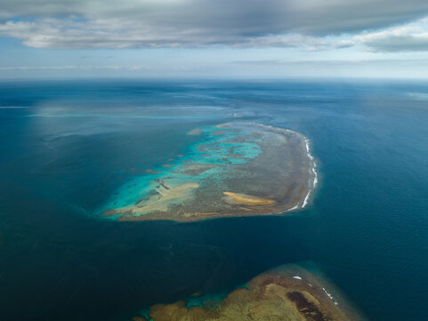 Aerial view of a submerged reef reveals a kaleidoscope of turquoise and tan hues against the deep blue sea, Goro, South Province, New Caledonia.