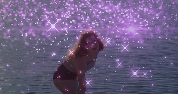 Beauty model in sea, bending to fix hair, turning toward camera while purple overlay obscuring