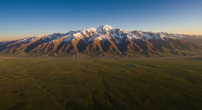 Aerial view of snow-capped mountain range and lush green valley at sunset