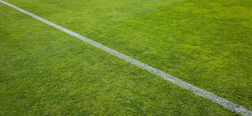 Obraz premium Close-Up Of Green Sports Field With Diagonal White Line On Grass Pitch For Soccer Or Football