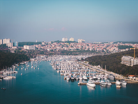 Aerial view of a myriad of white boats dance in the marina's embrace, juxtaposed against the red-tiled roofs and verdant coastline, Pula, Istria County, Croatia.