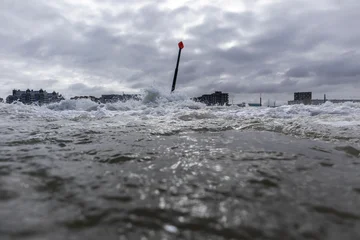 Fotobehang Noordzee Dramatic Wave Splashing Around wave breaker pole at Scheveningen Beach in cloudy Weather  © Frank