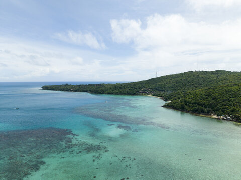 Aerial view of a tranquil coastline where turquoise waters meet lush greenery, a tropical paradise unfolds, Karimunjawa, Central Java, Indonesia.