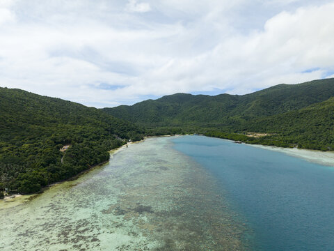 Aerial view of the vibrant turquoise waters meet lush green hills, a tranquil escape to paradise, Karimunjawa, Central Java, Indonesia.