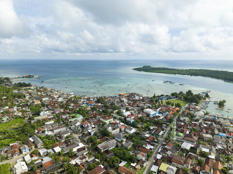 Aerial view of a vibrant coastal town nestled between lush greenery and turquoise waters, Karimunjawa, Central Java, Indonesia.