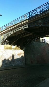 View from below of the Bridge of Lies in the Transylvanian city of Sibiu. Conveys historic engineering, ornamental metalwork, pedestrian-focused urban design, and cultural identity of old town streets