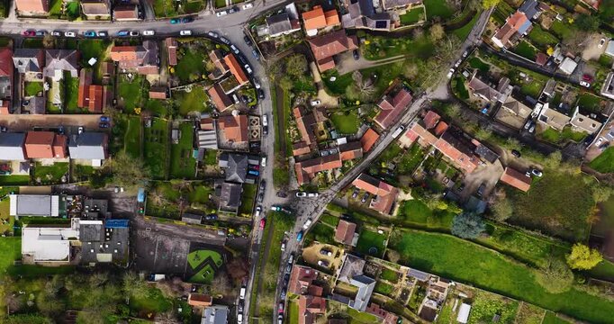 Top down aerial view of the village of Bishop Monkton with road with a narrow water channel trees houses gardens and parked cars showing a traditional rural village street in North Yorkshire in Spring