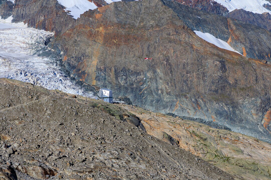 Helicopter delivering supplies to mountain hut Monte Rosa Hut at Monte Rosa massif with mountain glacier panorama in Pennine Alps, Switzerland