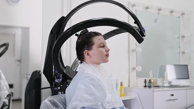 Professional hair treatment with climazone device in beauty salon, modern infrared equipment for coloring, restoration and care, female client during procedure, advanced haircare technology