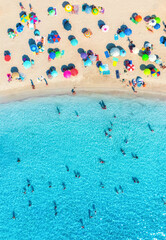 Obraz premium Aerial drone view of colorful umbrellas on sandy beach, swimming people in blue sea on sunny summer day. Top down view. Mallorca, Balearic Islands, Spain. Tropical. Clear turquoise water. Travel