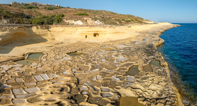 Aerial view of the intricate salt pans meeting the deep blue sea along the rocky coastline, Gozo, Malta.
