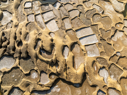 Aerial view of golden rock formations carved into geometric patterns, creating a textured landscape of light and shadow, Gozo, Malta.