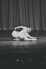 Graceful ballerina performing elegant pose on dimly lit swan lake stage © TRAVELARIUM