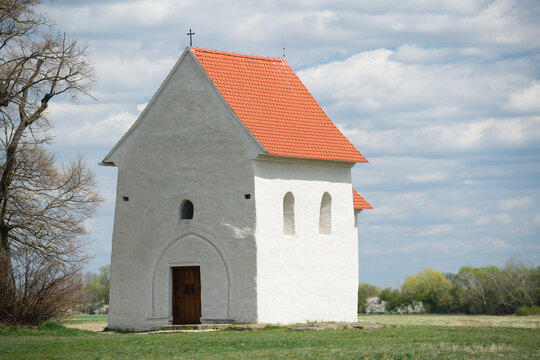 The Church of St. Margaret of Antioch in Kopcany, a historic pre-romanesque stone building with a red tiled roof standing in a rural spring landscape, Kopcany, Slovakia