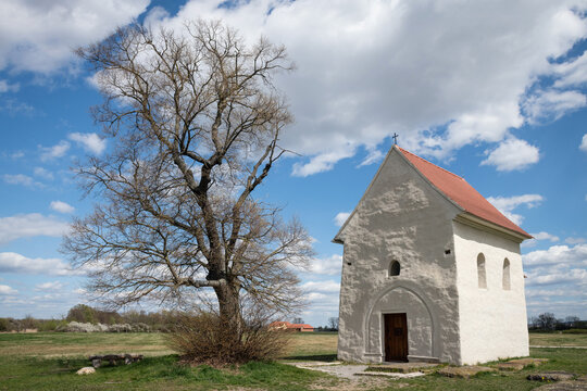 The Church of St. Margaret of Antioch in Kopcany, a 9th-century Great Moravian chapel standing next to an ancient linden tree under a dramatic spring sky, Kopcany, Slovakia