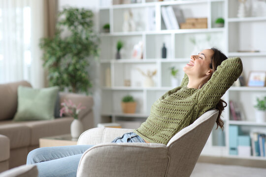 Happy woman relaxing sitting on armchair in the living room