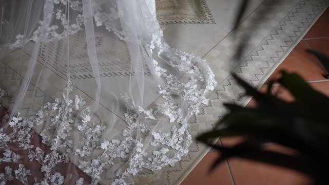 Close view of lace veil with floral embroidery spread on floor showing delicate fabric texture and wedding dress detail