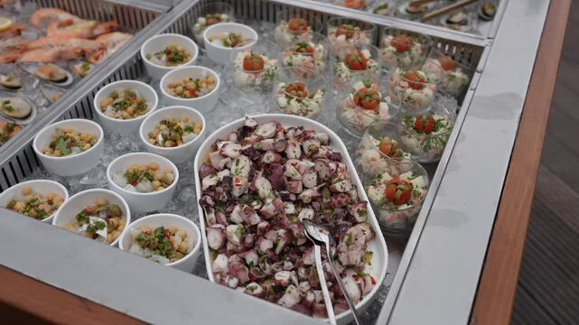 Assorted seafood appetizers with octopus salad and small portions served on ice display in catering buffet setup