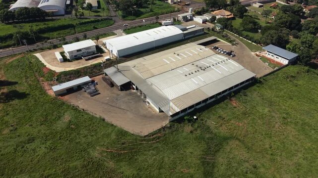 Aerial video footage of a large industrial complex in a rural area with green fields and trees