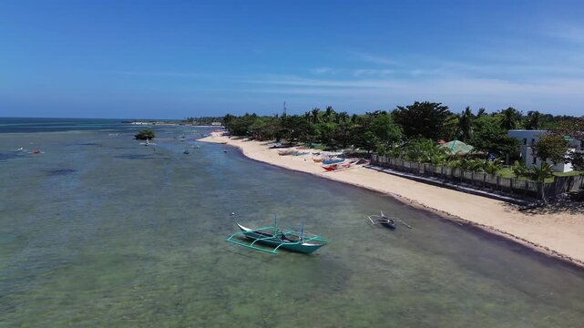 Aerial view of a tropical beach lined with palm trees and clear turquoise water with traditional Bangka boats creating a vibrant coastal scene on Bantayan Island Philippines Southeast Asia