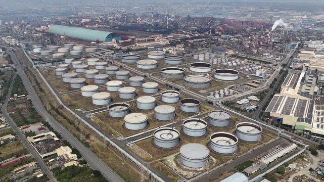 Expansive aerial view of an oil refinery and tank farm with rows of crude storage tanks, pipelines and processing units illustrating fossil fuel production and industrial infrastructure