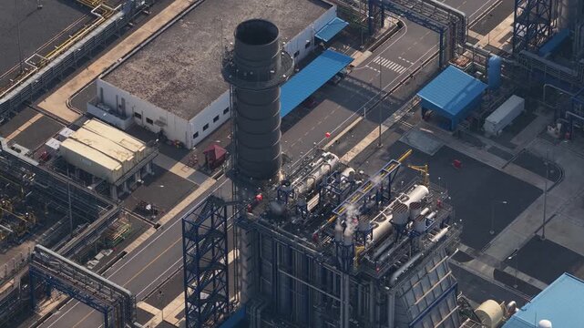 Aerial footage showing a large industrial power plant with pipelines and a smokestack, highlighting the infrastructure for energy production and distribution in a modern manufacturing facility