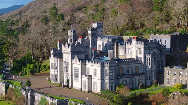 4K Cinematic Drone footage of Kylemore Abbey featuring calm water, mountain backdrop, and clear sunny conditions. Scenic and peaceful Irish landscape_11