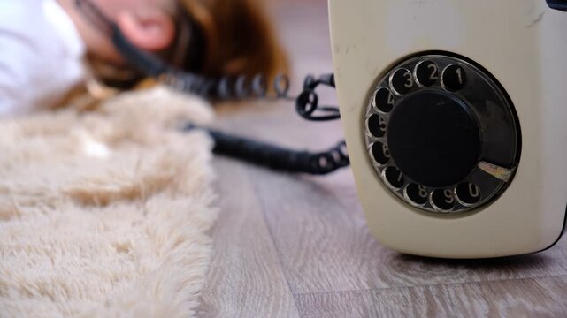 Teenager girl with a vintage rotary phone, lying on the floor and talking, smiling, whispering. Pretty teenager girl talking with friend	