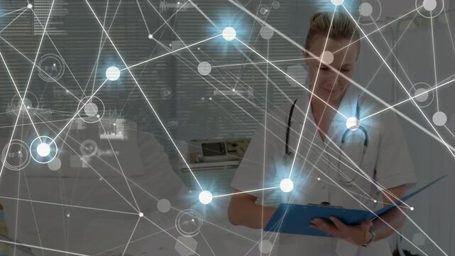 A doctor is writing on a clipboard and looking at the camera