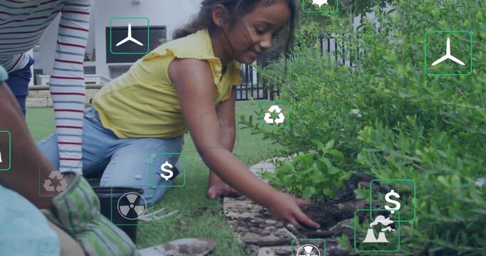 Child planting shrub in yard upon adult cue for learning, tamping mulch while eco icons floating