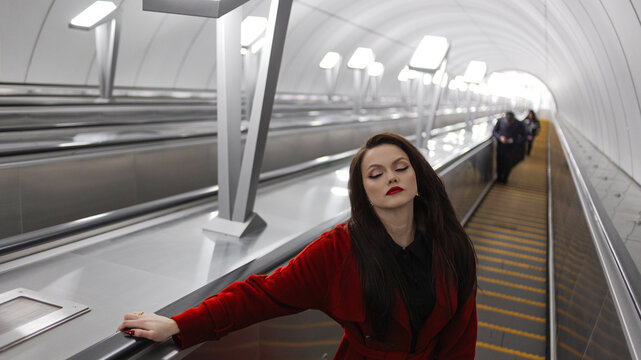 A stylish brunette riding an escalator up from a modern metro station