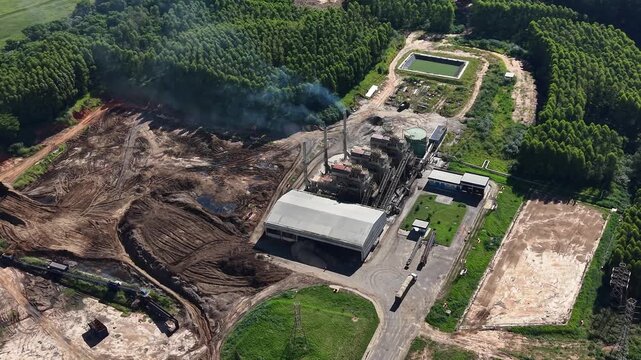 Aerial video footage of a large industrial site surrounded by trees and a body of water
