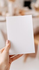 Fototapeta premium Hand hält leeres weißes Papier als Mockup in einem Café