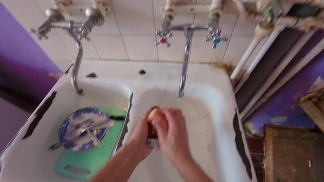 A man washes dishes with a sponge and dish detergent.  Washing plates and spoons in the dishwasher sink.  Cleaning dishes from leftovers. From the first person.